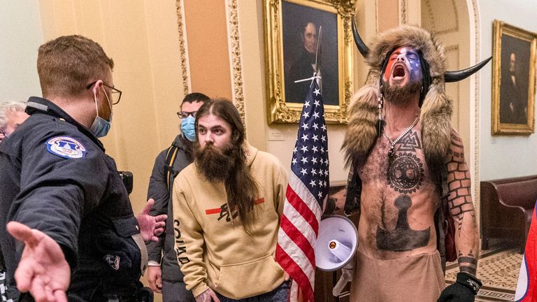Jacob Chansley (R), known as the 'QAnon Shaman', was jailed over the riot