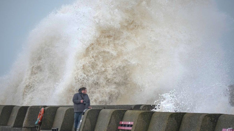 People view the waves created by high winds and spring tides hitting the sea wall at New Brighton promenade on February 17, 2022 in Liverpool, England